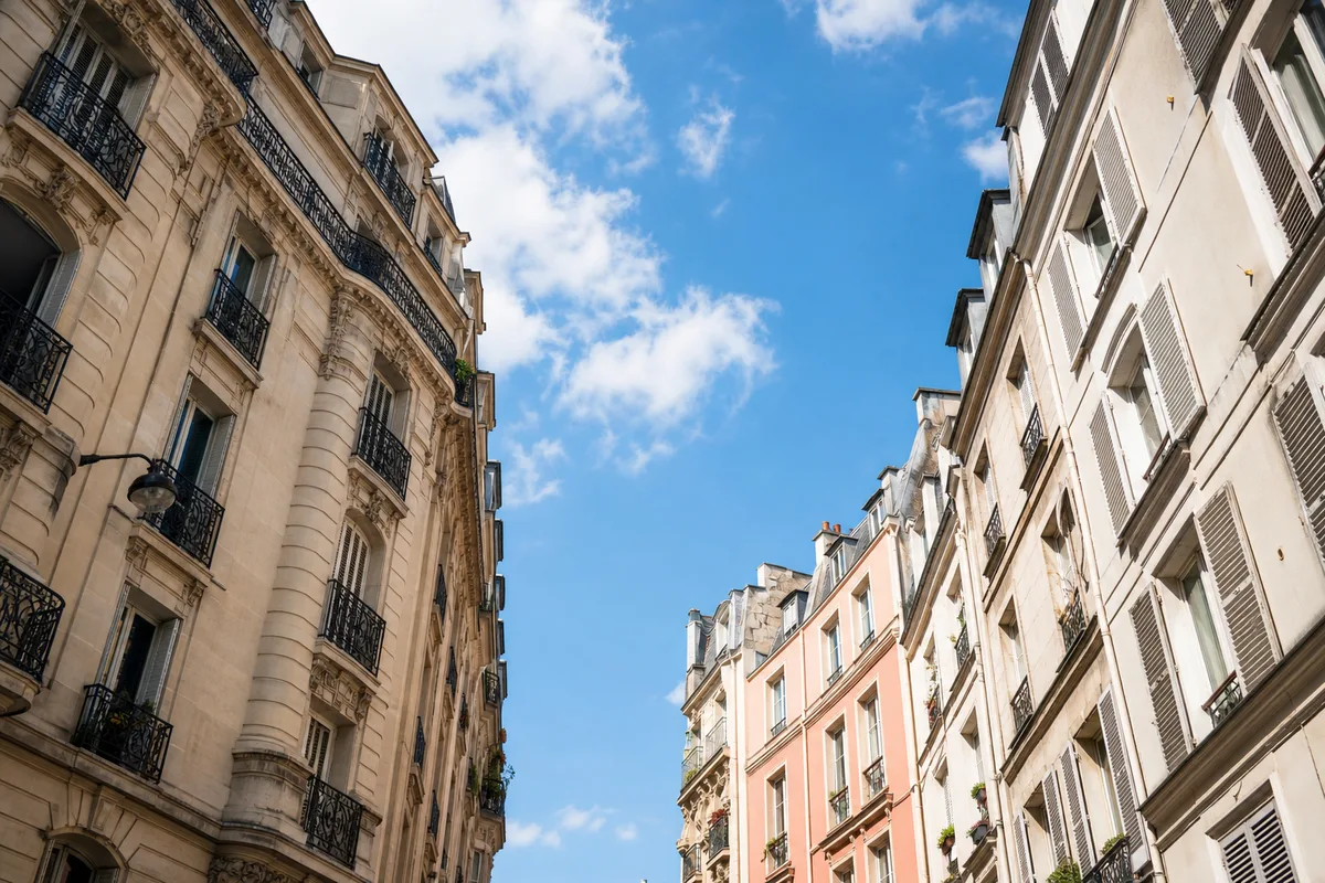 Façades d’immeubles et de maisons d’une rue française vue en contre-plongée sous un ciel dégagé